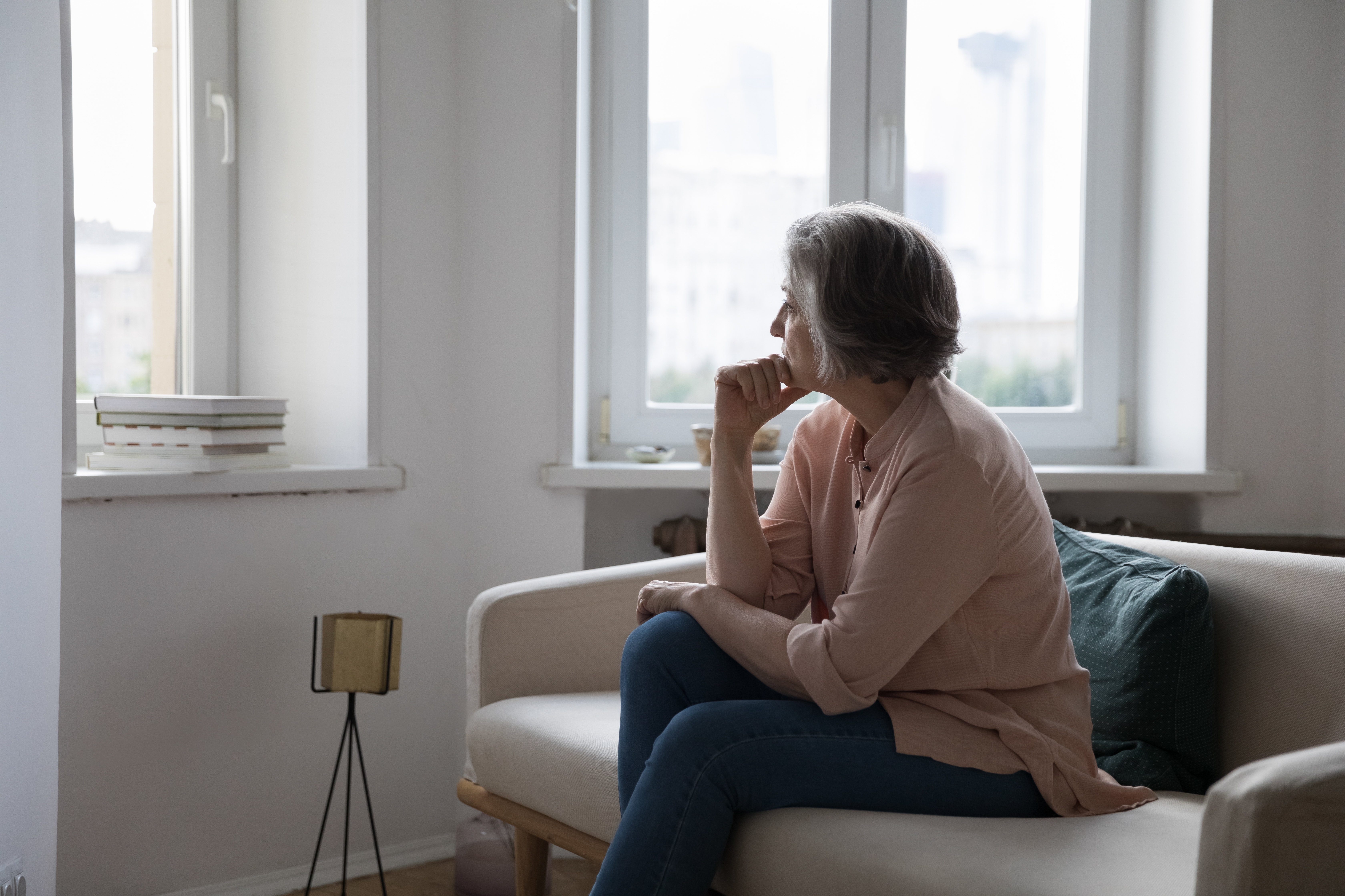 Middle aged woman looking at window sadly, contemplating health issues